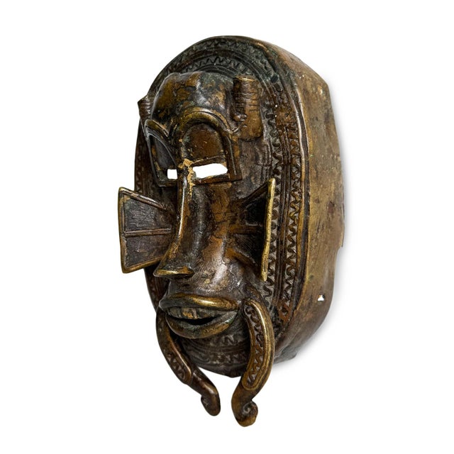 Striking Senufo-style cast bronze mask from Western Africa. This piece reflects the refined visual language associated...
