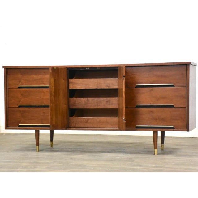 A mid century modern walnut nine drawer dresser with brass accents. Professionally refinished. 66” wide. 18” deep. 31” tall.