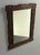 Wall mirror in a dark stained wooden frame, carved by hand with a rose in each corner and sprays of serrated leaves along...