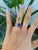 A solid natural boulder opal cabochon flashes with vivid play of color in a freeform oval at the centre of this solid 14K...