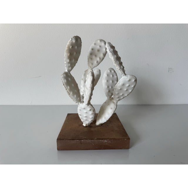 Charming vintage cactus sculpture crafted from painted white metal, mounted on a metal base. This sculptural piece...