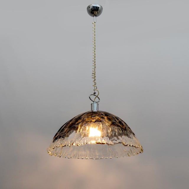 This pendant lamp features a transparent murano blown glass bell-shaped lampshade with blue, black and brown murrine...