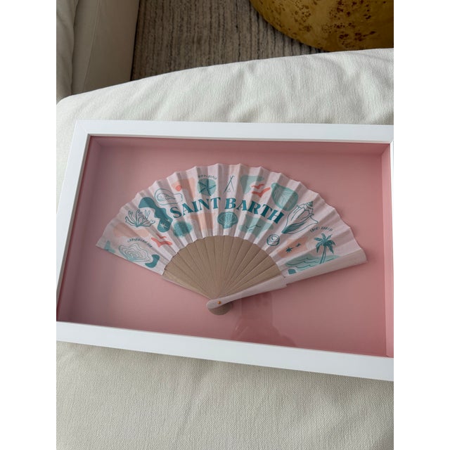 An original Nikki Beach St. Barth fan, artfully preserved in a custom shadow-box presentation. Set against a soft blush...