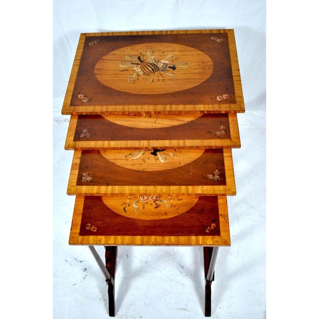A 20th century sheraton style nest of tables in mahogany with satinwood crossbanding, and hand painted musical...