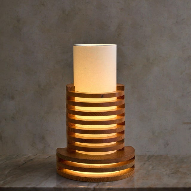 A French table lamp from the 1970s, crafted from stacked solid wood rings. The cylindrical form rises in measured tiers,...