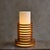 A French table lamp from the 1970s, crafted from stacked solid wood rings. The cylindrical form rises in measured tiers,...