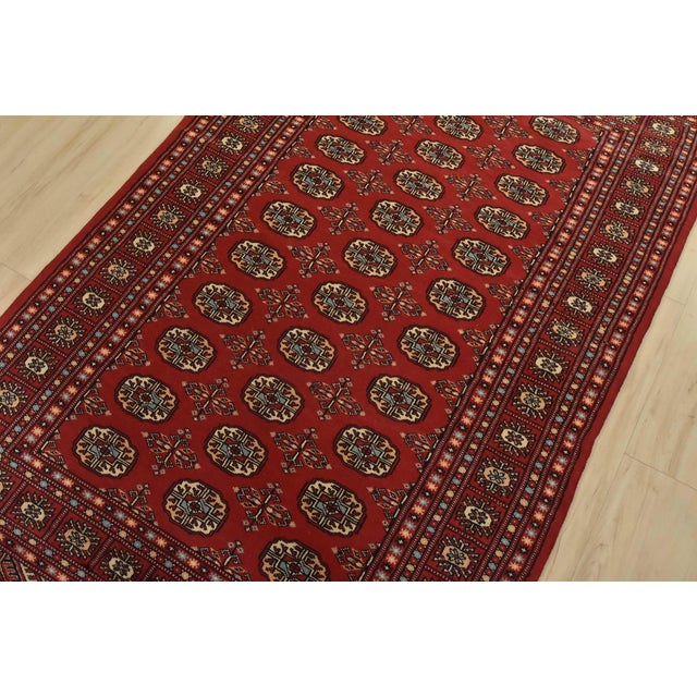 A tribal Bokhara rug hand-knotted with fine wool on a cotton foundation. This rug features rows of repeating medallions...