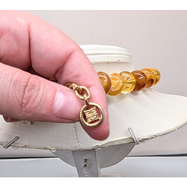 Circa 1990s goldtone oval shaped three different shades of faux-amber alternating colored beads varying between...