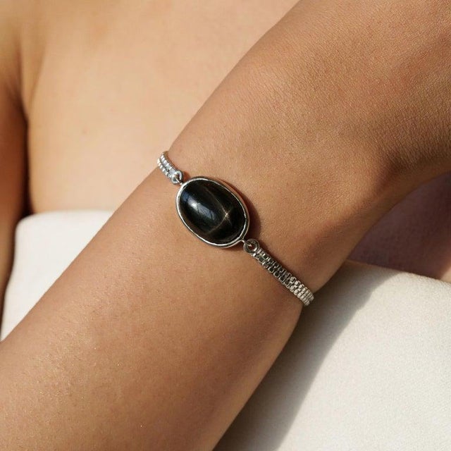 A sculptural black star cabochon bracelet in 925 sterling silver, defined by its singular, statement-making form. The...