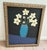 Large primitive style whimsical framed painting of joyful flowers in a blue vase against a stark black background and...