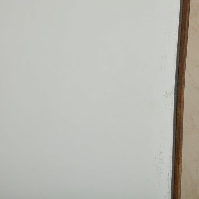 A vintage organic form wall mirror featuring subtle curves and rounded corners. This mirror has a delicate, thin brass...