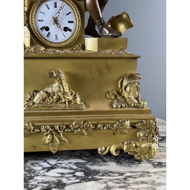 An important Empire period clock in gilt and patinated bronze, depicting a draped male figure in the antique style, seated...
