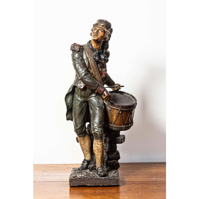 This 19th-century French sculpture features a young drummer, captured in a moment of intense focus and energy. Rendered in...