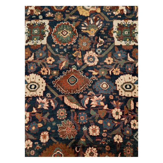 This early 20th-century Persian Bidjar rug presents a richly detailed allover floral composition across a deep navy field....