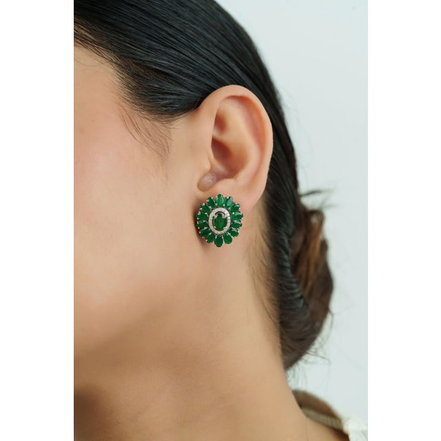 These floral stud earrings showcase 7.47 carats of natural emeralds of oval cut set in 14k white gold. The center oval...