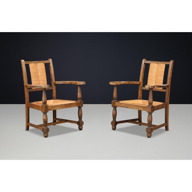 Pair of French Oak and Rush Armchairs in the Manner of Charles Dudouyt, France, 1940s A beautiful and characterful pair of...