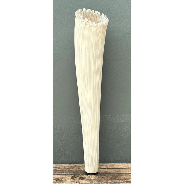 This floor lamp takes a striking, elongated cone shape, its silhouette tapering dramatically from a wide, ruffled opening...