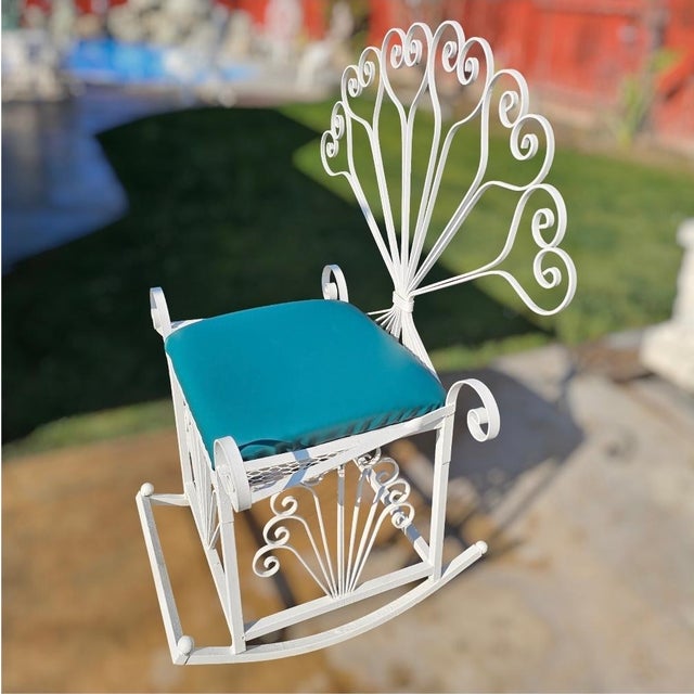 This monumental vintage wrought-iron peacock Rocking chair, in the Salterini style, features an exaggerated fan back with...