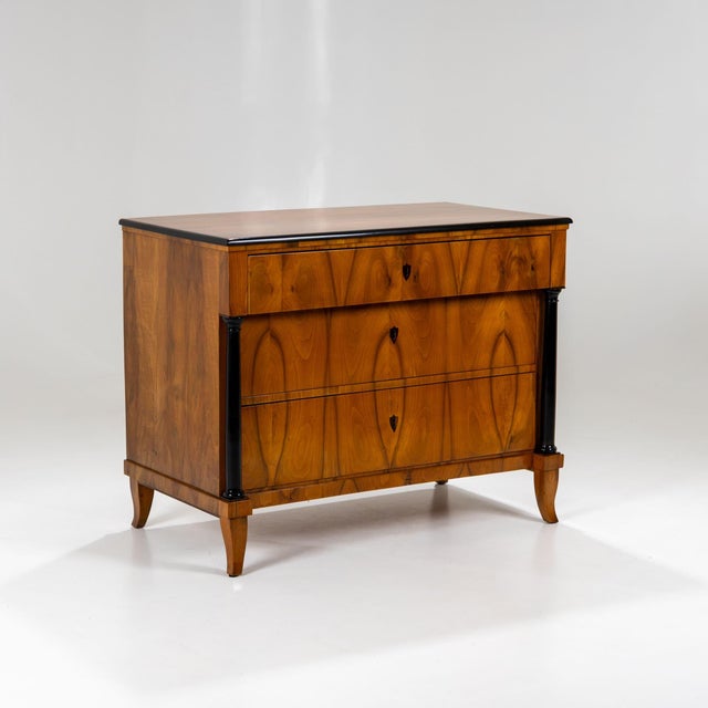 Franconian Biedermeier chest of drawers veneered in cherrywood, featuring three drawers flanked by ebonized columns and...
