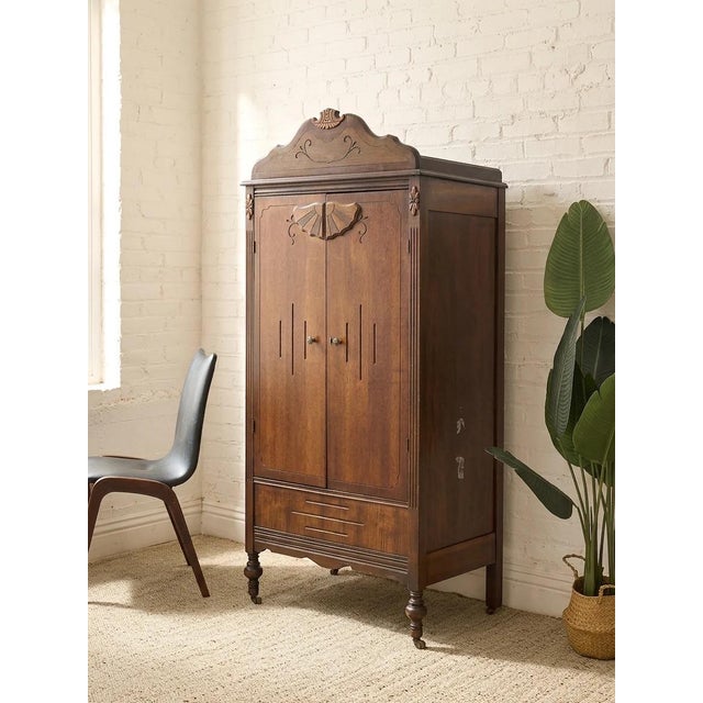 A character-rich antique wood cabinet with a tall, narrow silhouette and wonderfully decorative carved details. The shaped...