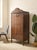 A character-rich antique wood cabinet with a tall, narrow silhouette and wonderfully decorative carved details. The shaped...