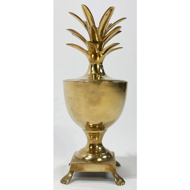 Vintage Hollywood Regency style brass pineapple lidded urn featuring claw feet and exaggerated plume. Top can hold a...