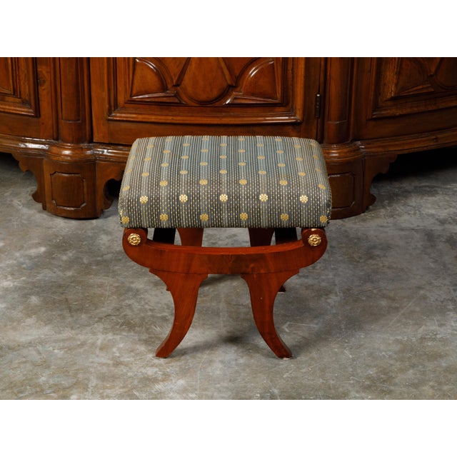 An Austrian Biedermeier period walnut stool from the 19th century, with upholstered seat and gilt rosettes. Created in...