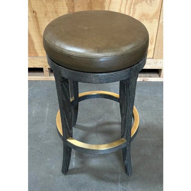 Grey Cerused Finish on Rift Oak. Satin Brass Footrest. Upholstered in Leather. Swivel Mechanism Included. From the...