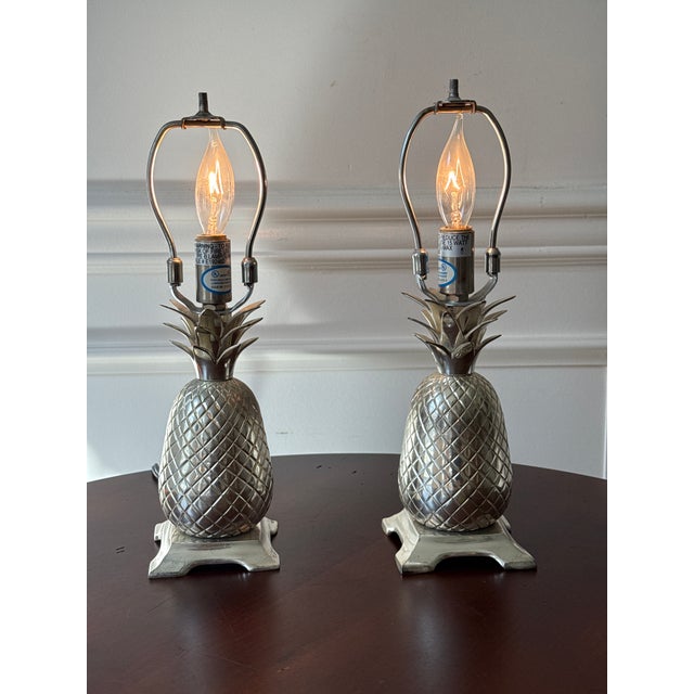 A symbol of hospitality, pineapples are frequently included in homes. This silver plated brass pair of petite footed...