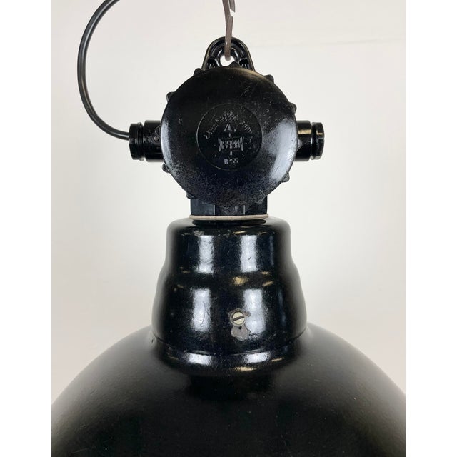 Industrial enamel factory light made by Lbd Veb Leuchtenbau Dresden in East Germany during the 1950s. It features black...