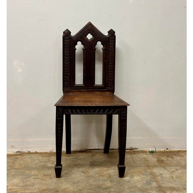 A striking antique English Gothic Revival chair, rich with the architectural spirit that defined the Gothic revival...