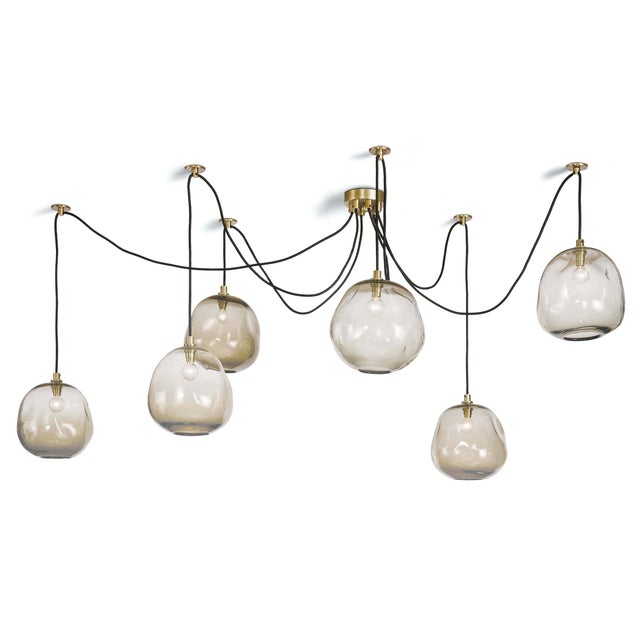 This chandelier’s hand-crafted glass shades suspended from rope cords lend a distinct, artisan effect that can create a...