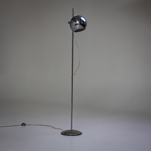 Floor lamp in chromed metal with a spherical shade mounted on a slender smooth stem and slightly domed base. Labeled on...