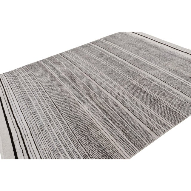 Hand knotted in wool, this 9x12 contemporary rug “Sky” features geometric stripes, and is more emphatic of the gradation...