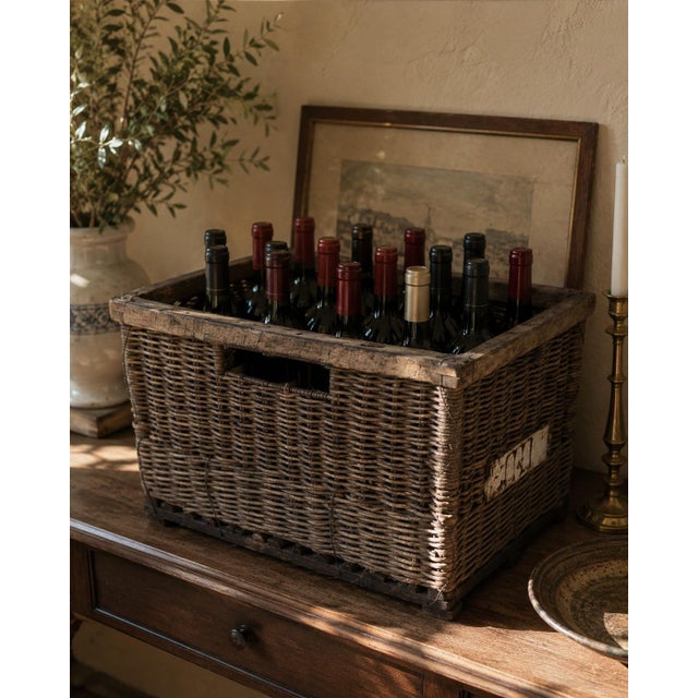 An evocative early-20th-century French wine crate constructed from dark, tightly woven wicker over a substantial wooden...