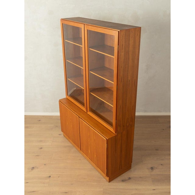 Classic two-part display cabinet from the 1960s. Teak veneer body with two glass doors, two solid doors, eight shelves,...