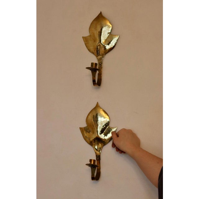 Made in Sweden. Two exquisite brass candle sconces from the Mid Century era, meticulously handcrafted with a stunning...