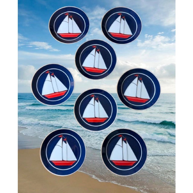 A great vintage set of 8 plates nautical themed design with a stylized red and white sailboat centered on a deep blue...