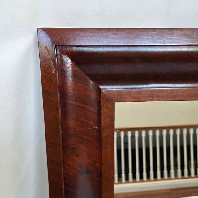 A handsome late-19th-century wall mirror featuring a substantial figured/flamed mahogany veneer frame with deep ogee...