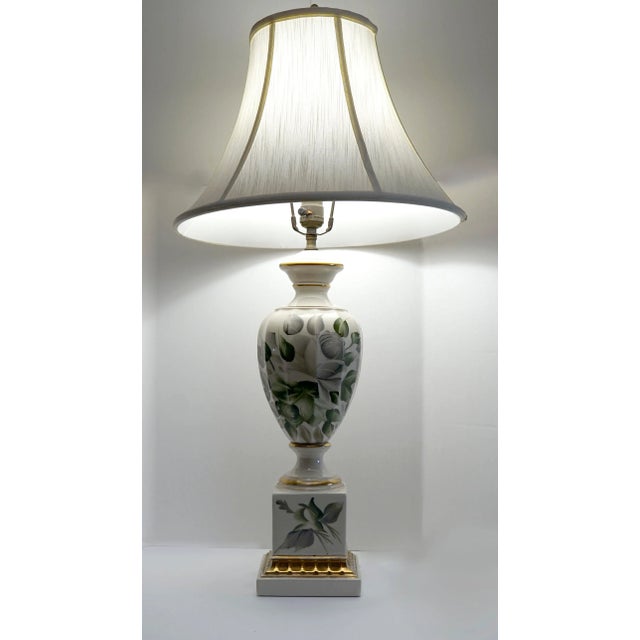 This vintage lamp features hand-painted decoration of botannical leaves on white porcelain. The lamp is accented with gilt...