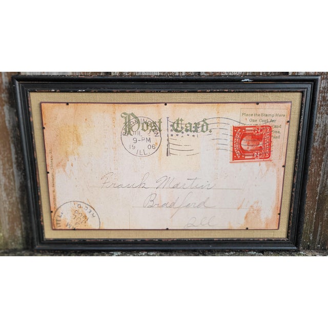 This vintage two dimesional post card image on wood is framed with no glass and it is set on a burlap background. It has a...