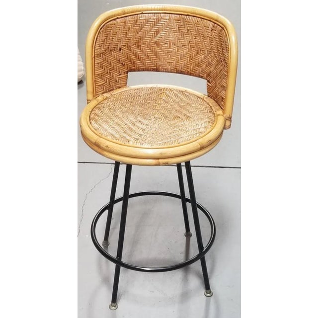 Rattan and wicker bar stool with swivel iron bases by Seng of Chicago. This chair features a wicker seat and back and...