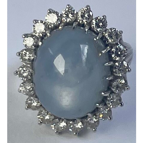 An elegant vintage cocktail ring with a beautiful pale lavender-blue cabochon sapphire surrounded by 20 diamonds in a 14K...