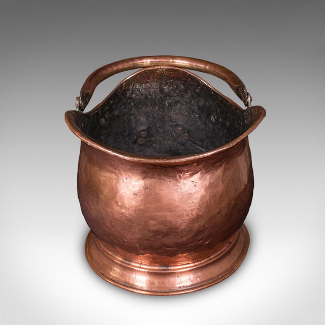 This is an antique helmet coal scuttle. An English, copper fireside store or fuel keeper, dating to the early Victorian...