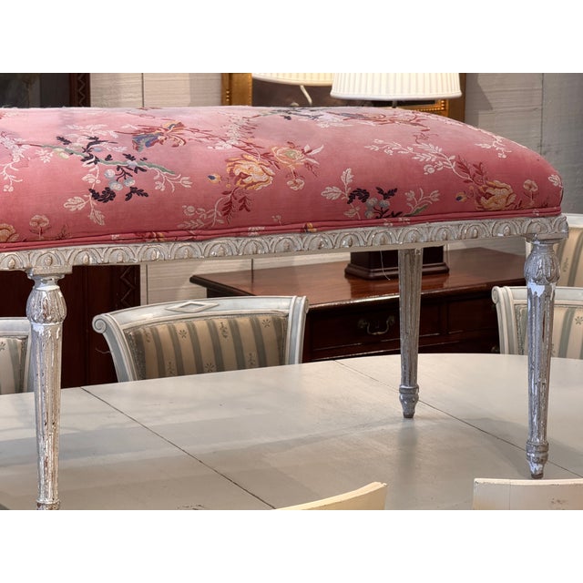 A long and graceful Louis XVI banquette with a painted frame in soft gray-white. The seat rail is carved with a continuous...