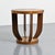 Art Deco side table with a circular top featuring marquetry decoration and resting on four curved legs connecting the top...