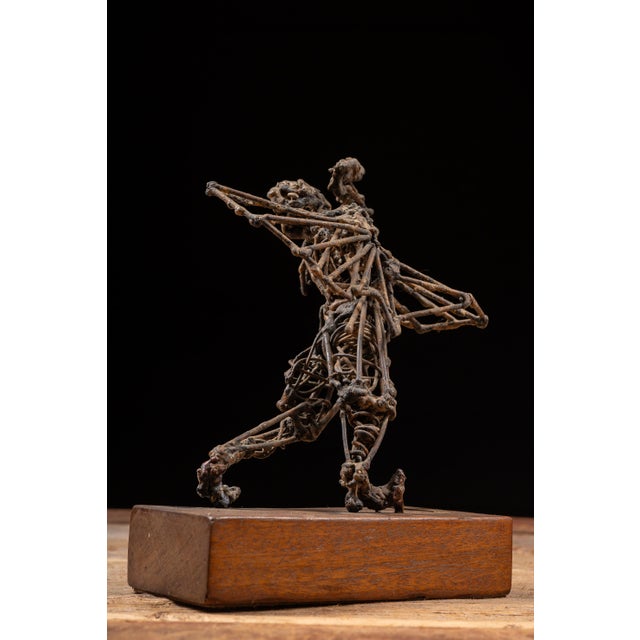 Expressive welded steel figural sculpture depicting an abstract human form in a dynamic, lunging pose with one arm raised...