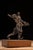 Expressive welded steel figural sculpture depicting an abstract human form in a dynamic, lunging pose with one arm raised...