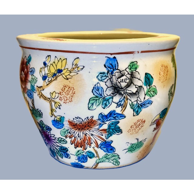A charming hand‑painted Chinese ceramic bowl featuring a colorful floral and bamboo motif with birds and a red floral...