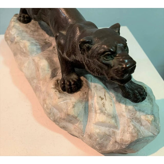 Bronze lioness in position on stone.